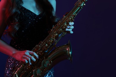 Photo of Professional musician playing saxophone on color background, closeup. Space for text