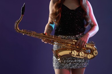 Photo of Professional musician with saxophone on color background, closeup