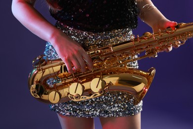 Photo of Professional musician with saxophone on color background, closeup