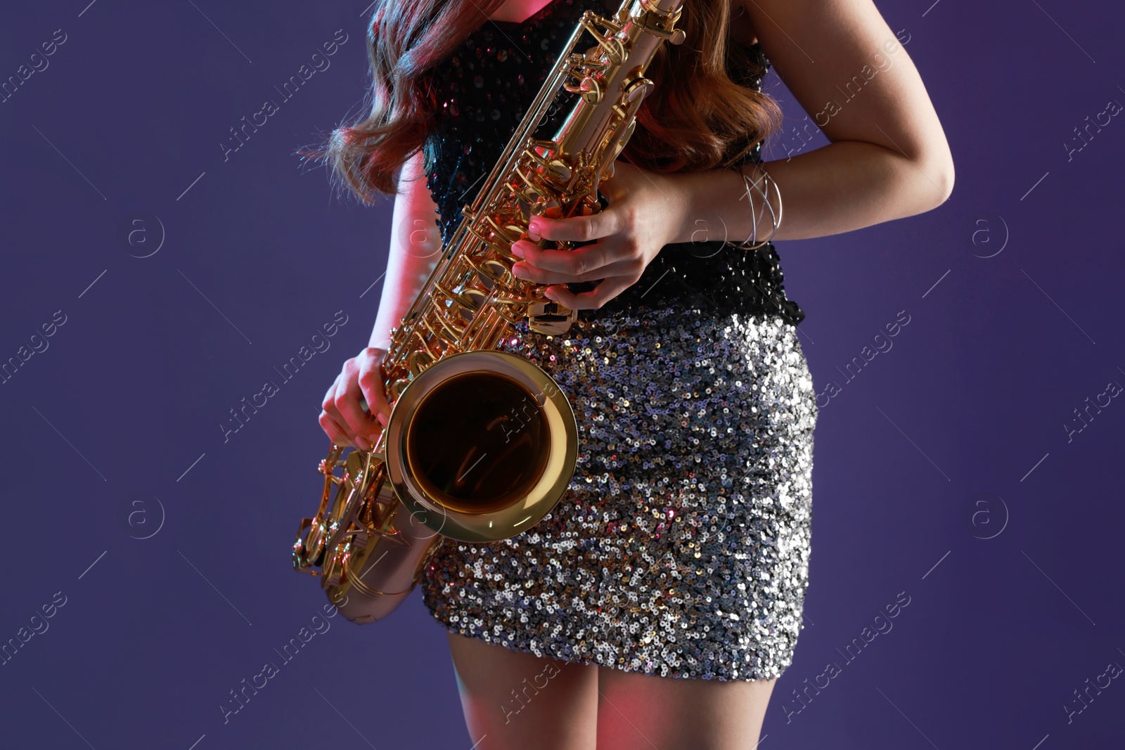 Photo of Professional musician playing saxophone on color background, closeup