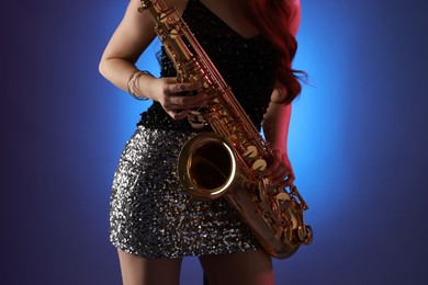 Photo of Professional musician playing saxophone on color background, closeup