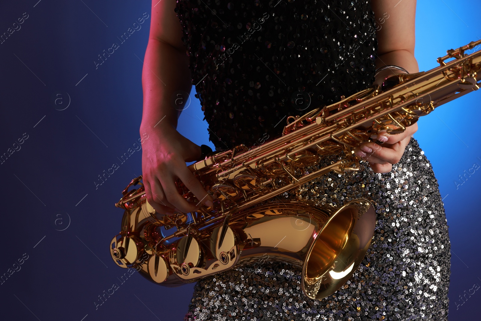 Photo of Professional musician with saxophone on color background, closeup