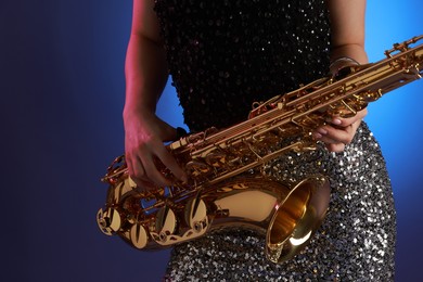 Photo of Professional musician with saxophone on color background, closeup