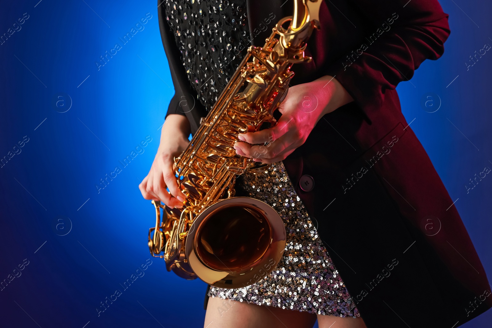 Photo of Professional musician with saxophone on color background, closeup