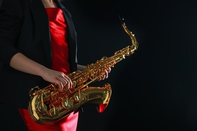 Photo of Professional musician with saxophone on black background, closeup