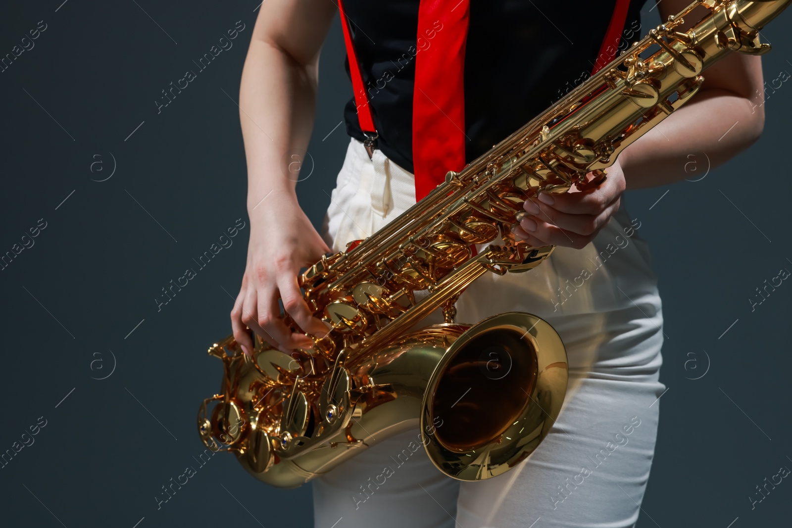 Photo of Professional musician with saxophone on grey background, closeup