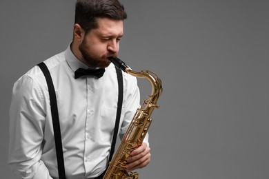 Photo of Professional musician playing saxophone on grey background. Space for text