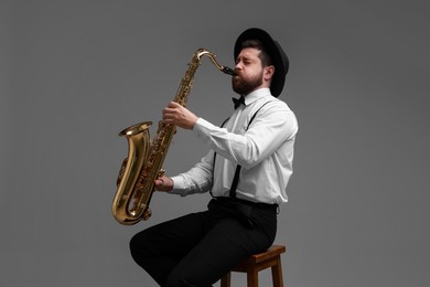 Photo of Professional musician playing saxophone on grey background