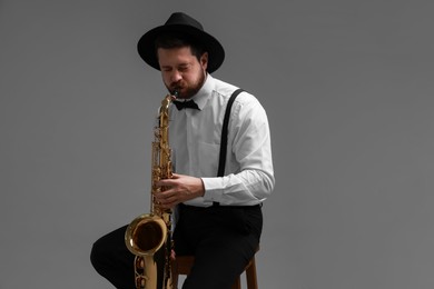 Professional musician playing saxophone on grey background