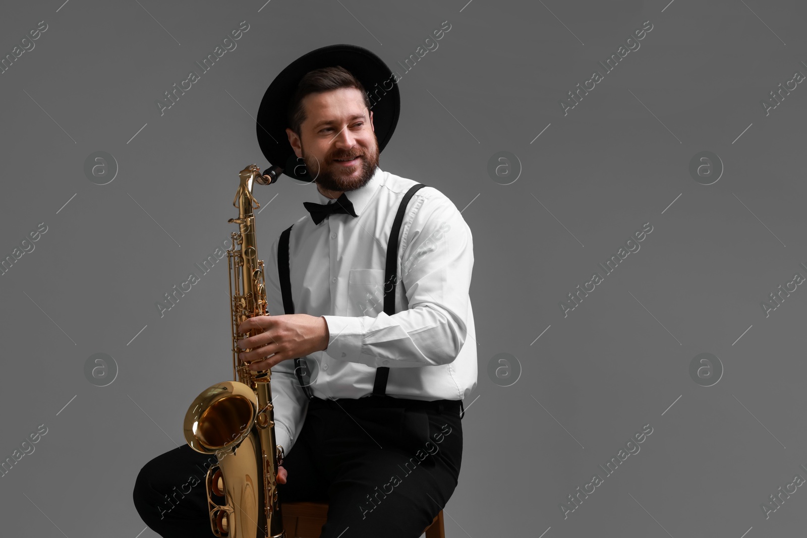 Photo of Professional musician with saxophone on grey background. Space for text