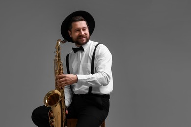 Photo of Professional musician with saxophone on grey background. Space for text