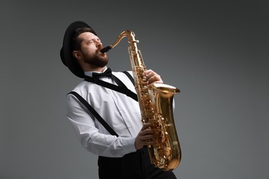 Professional musician playing saxophone on grey background