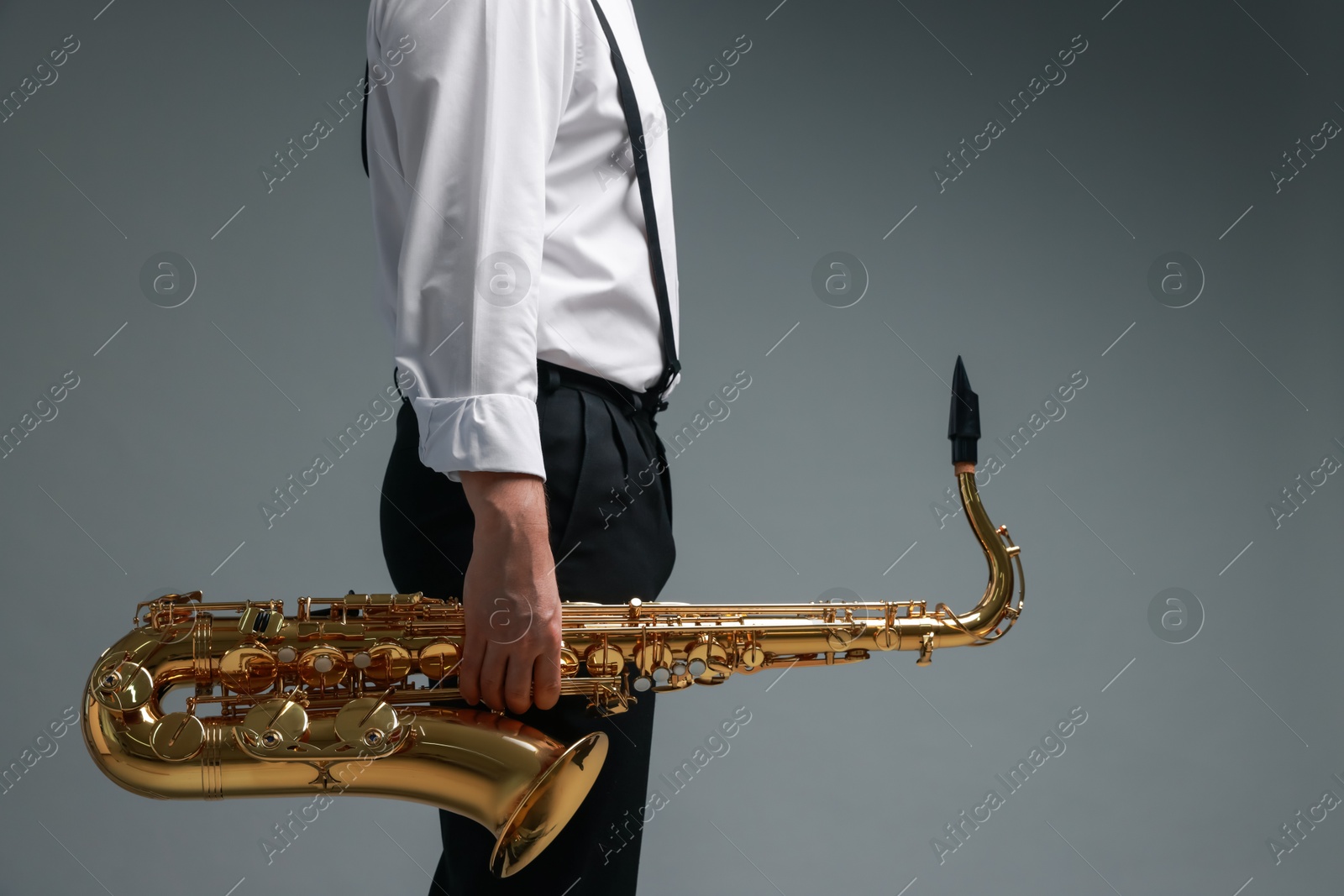 Photo of Professional musician with saxophone on grey background, closeup