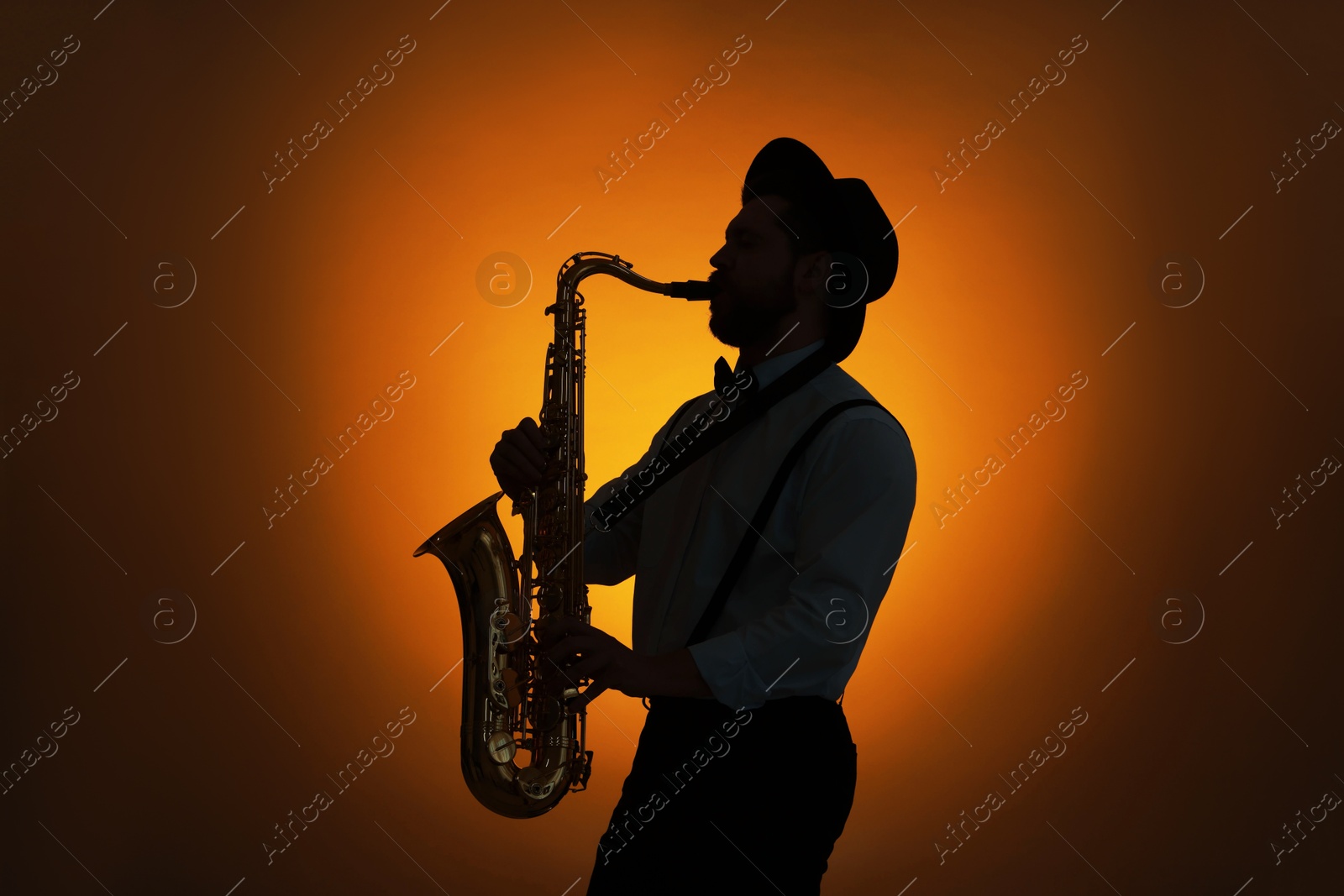 Photo of Professional musician playing saxophone on color background, backlit