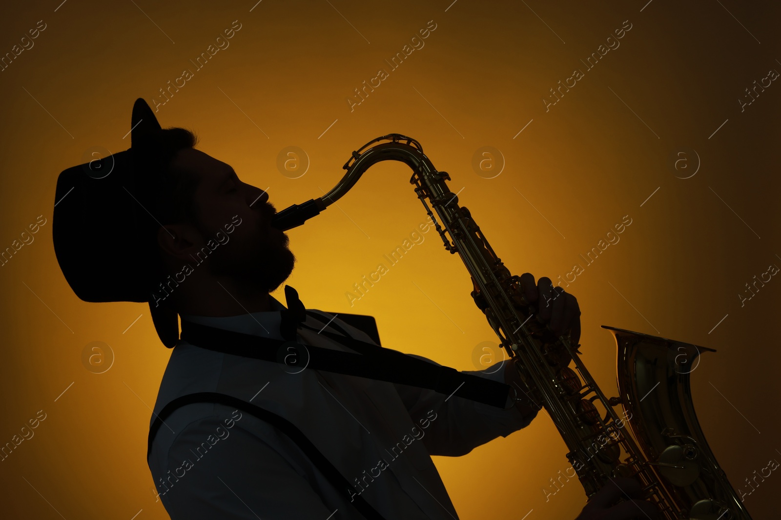 Photo of Professional musician playing saxophone on color background, backlit