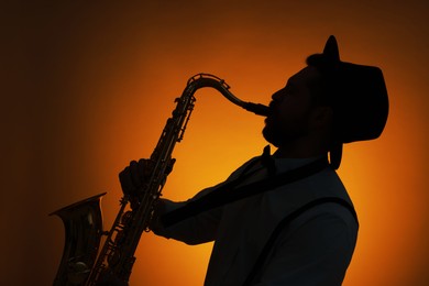 Photo of Professional musician playing saxophone on color background, backlit