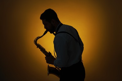 Professional musician playing saxophone on color background, backlit