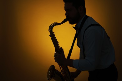 Professional musician playing saxophone on color background, backlit