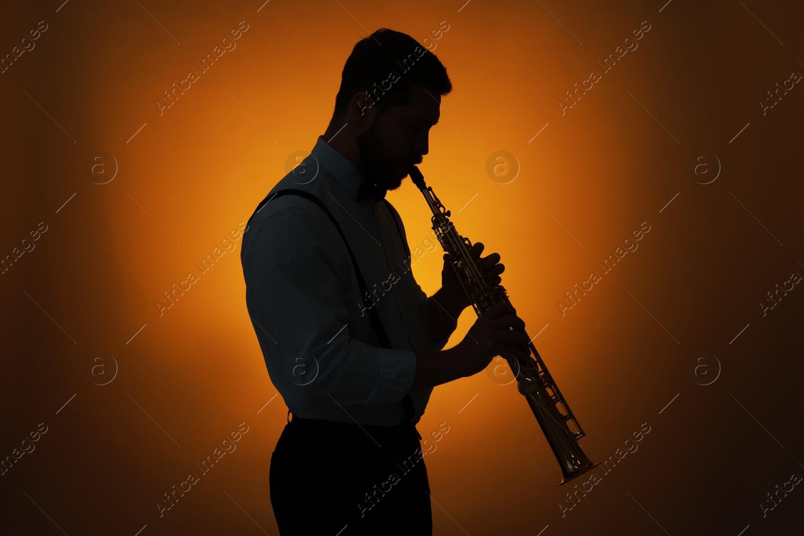 Photo of Professional musician playing soprano saxophone on color background, backlit