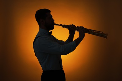 Photo of Professional musician playing soprano saxophone on color background, backlit