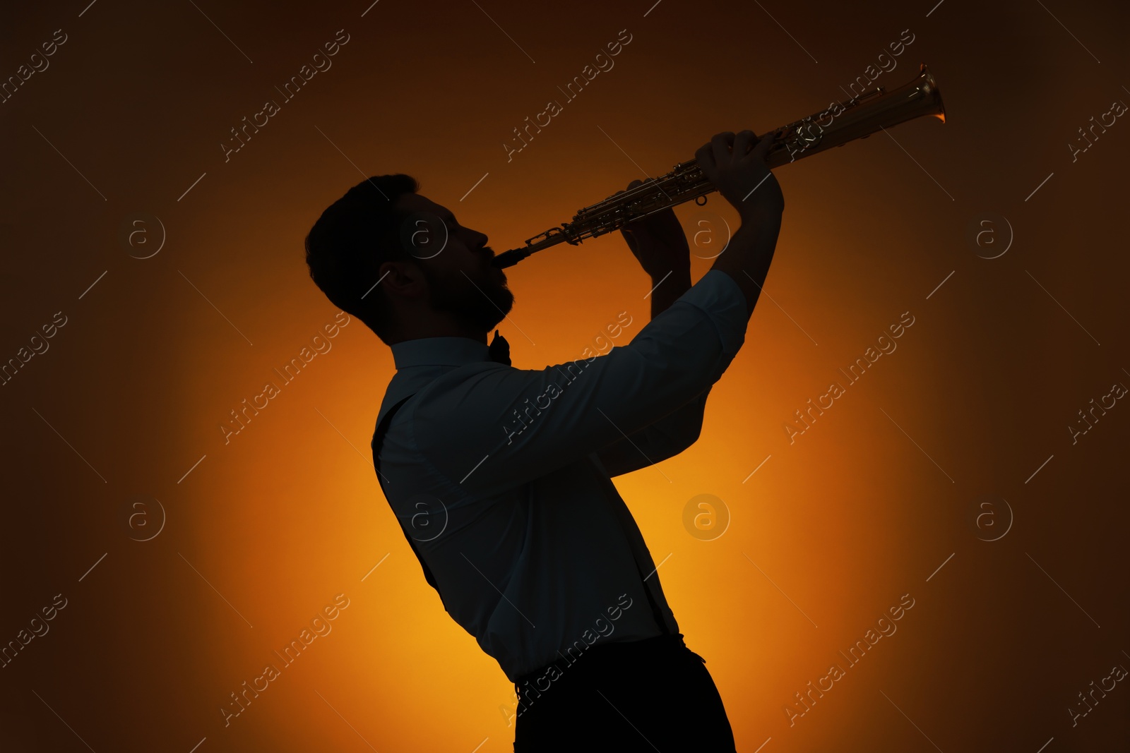 Photo of Professional musician playing soprano saxophone on color background, backlit