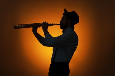 Photo of Professional musician playing soprano saxophone on color background, backlit