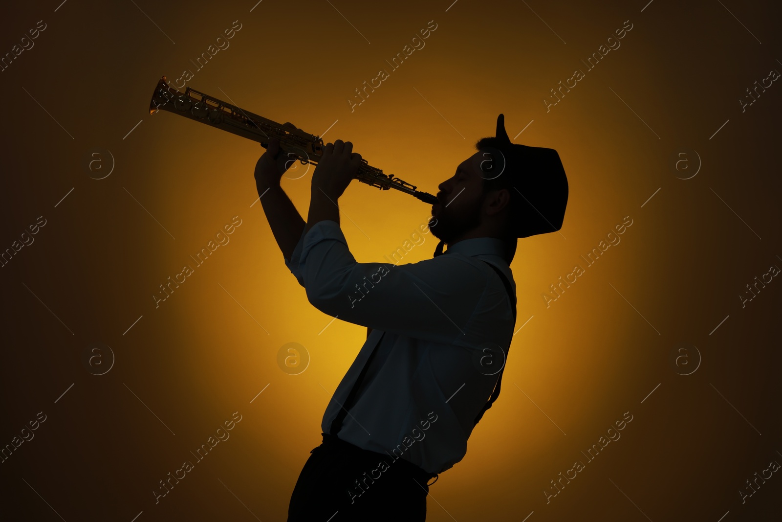 Photo of Professional musician playing soprano saxophone on color background, backlit