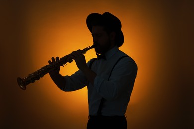 Photo of Professional musician playing soprano saxophone on color background, backlit