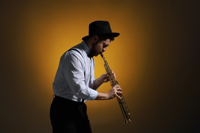 Professional musician playing soprano saxophone on color background