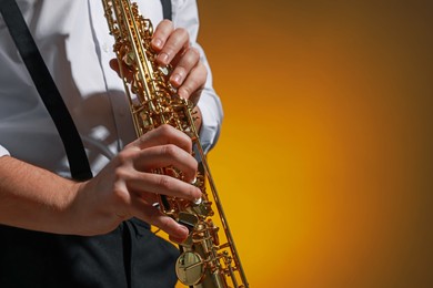 Photo of Professional musician playing soprano saxophone on color background, closeup. Space for text