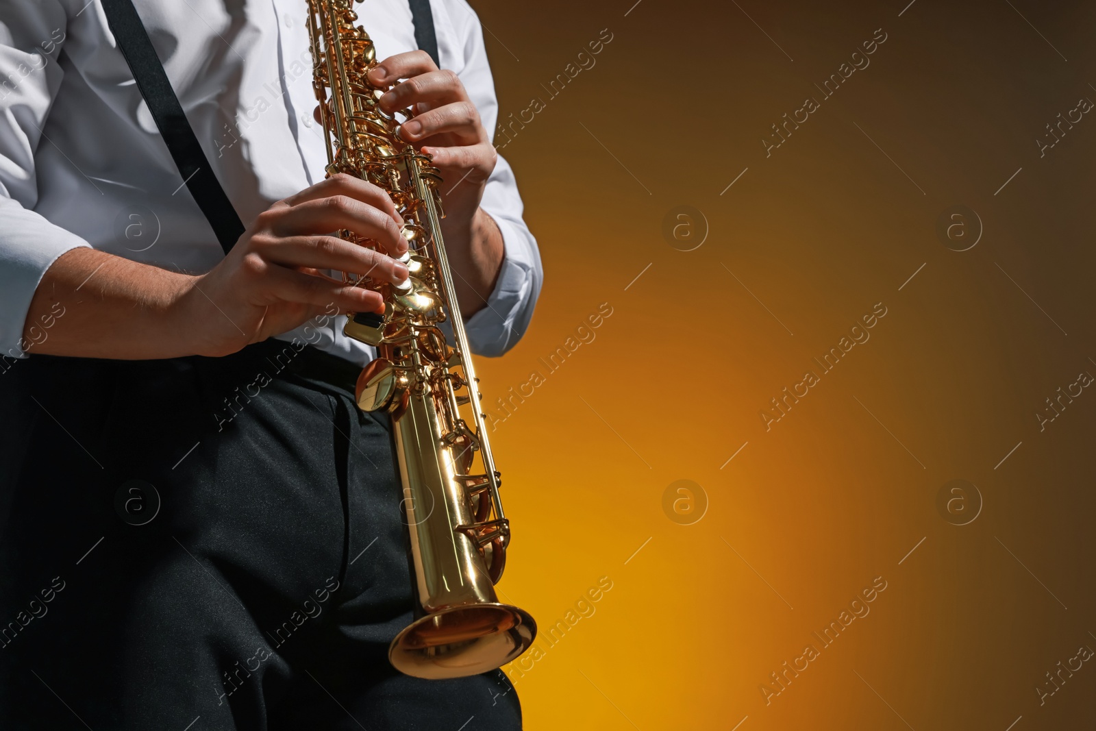 Photo of Professional musician playing soprano saxophone on color background, closeup. Space for text