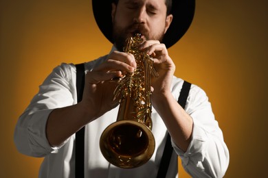 Photo of Professional musician playing soprano saxophone on color background, closeup