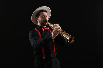 Professional musician playing soprano saxophone on black background