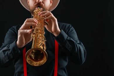 Photo of Professional musician playing soprano saxophone on black background, closeup