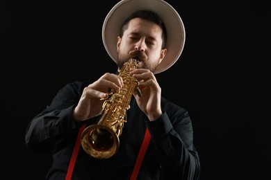 Professional musician playing soprano saxophone on black background