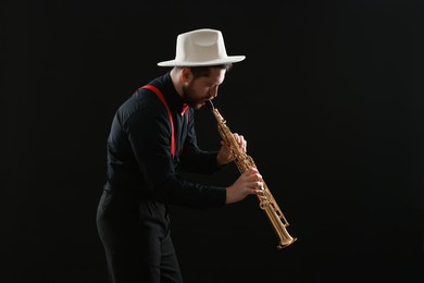 Professional musician playing soprano saxophone on black background