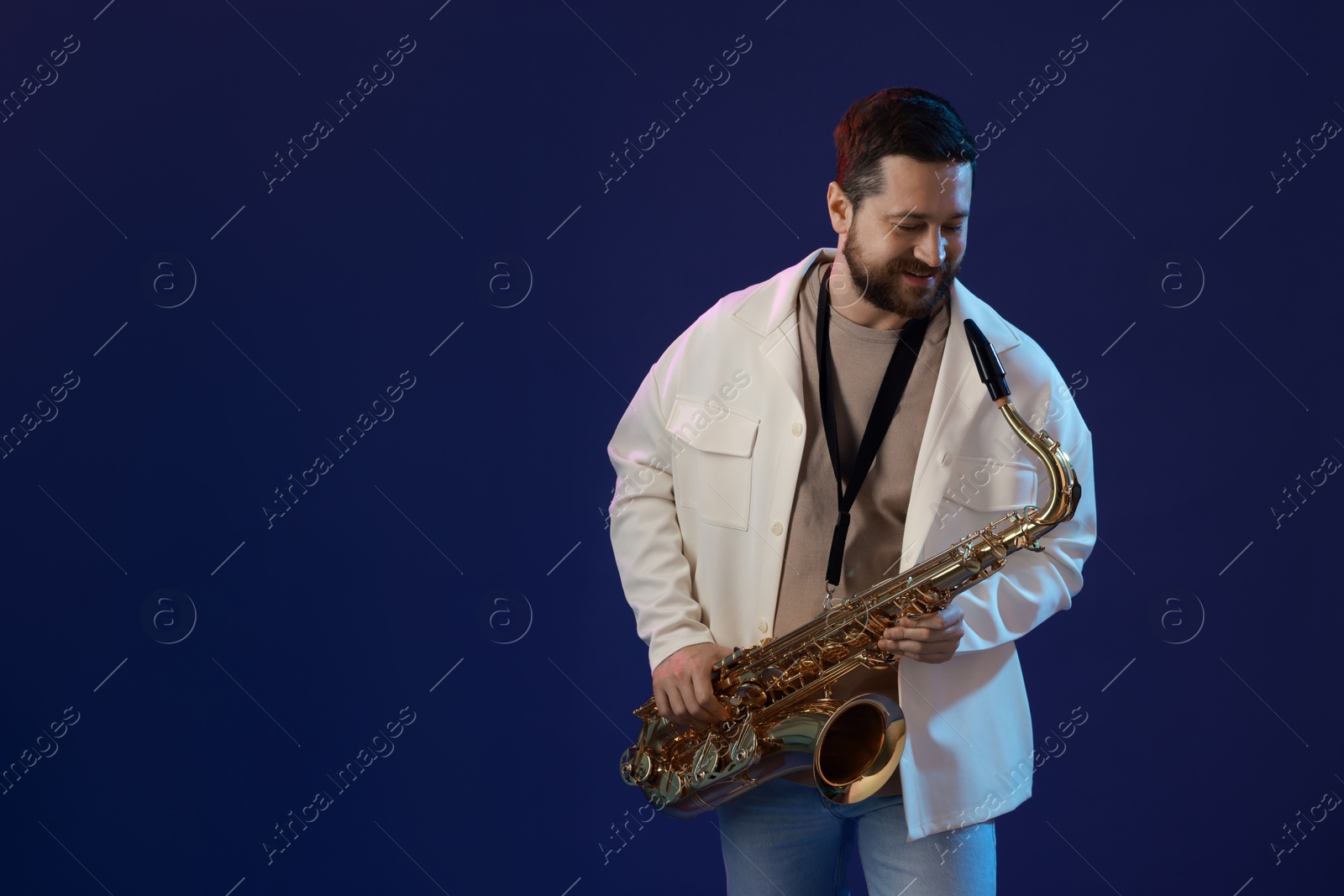 Photo of Professional musician with saxophone on blue background. Space for text