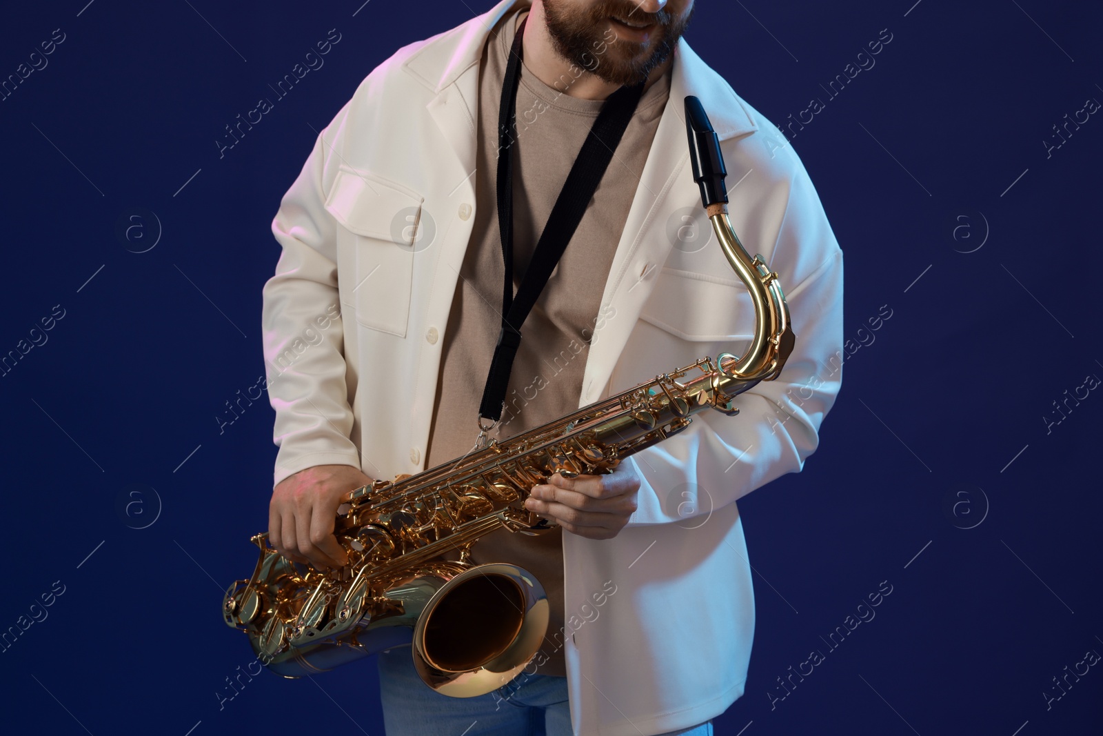 Photo of Professional musician playing saxophone on blue background, closeup