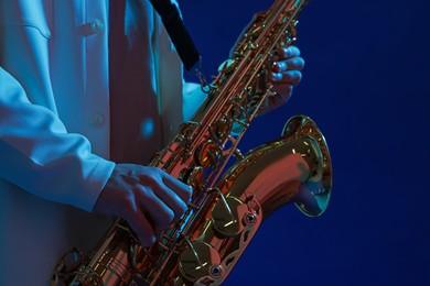 Photo of Professional musician playing saxophone on blue background, closeup