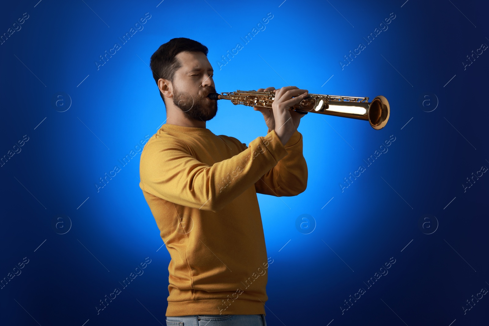 Photo of Professional musician playing soprano saxophone on blue background