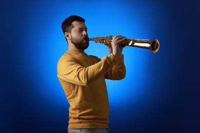 Professional musician playing soprano saxophone on blue background