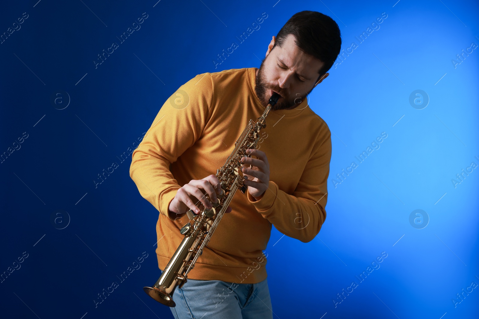 Photo of Professional musician playing soprano saxophone on blue background