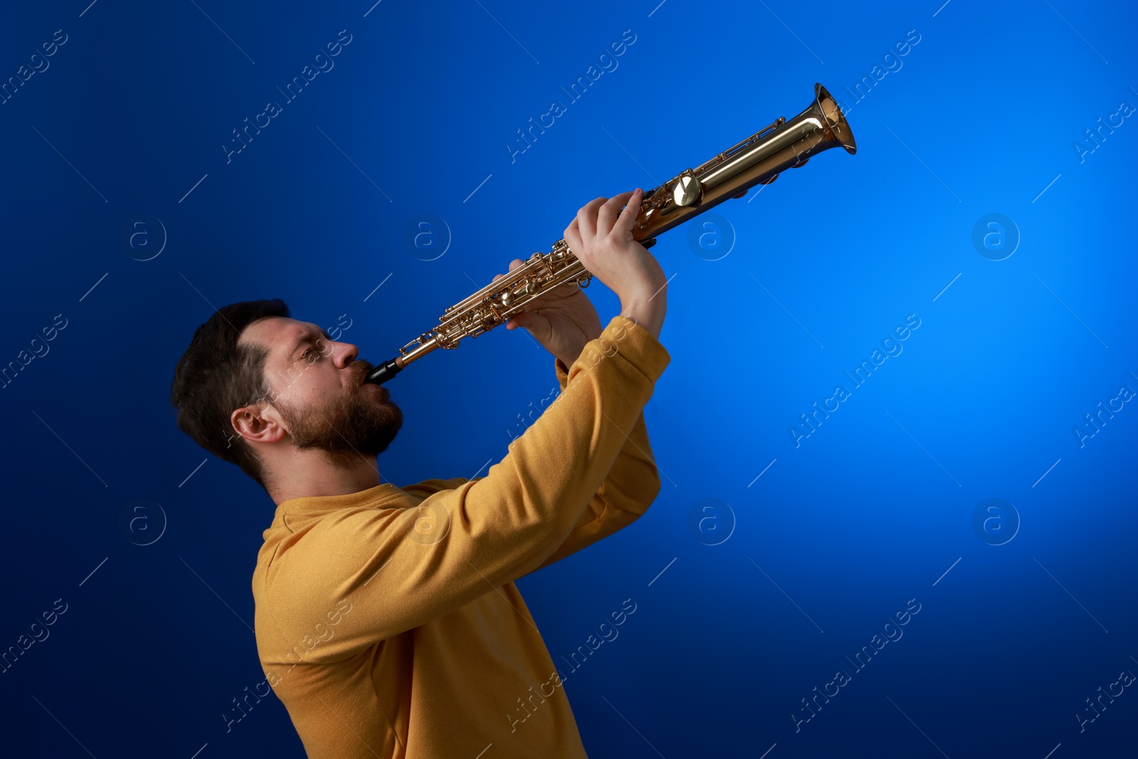 Photo of Professional musician playing soprano saxophone on blue background