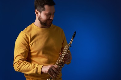 Photo of Professional musician with soprano saxophone on blue background. Space for text