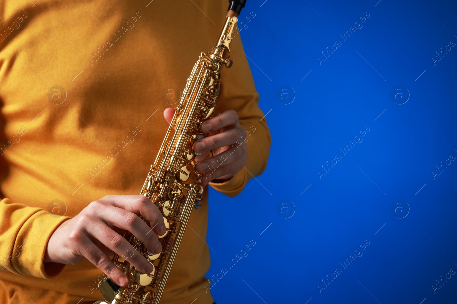 Photo of Professional musician with soprano saxophone on blue background, closeup. Space for text