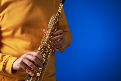 Photo of Professional musician with soprano saxophone on blue background, closeup. Space for text