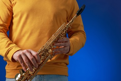 Photo of Professional musician with soprano saxophone on blue background, closeup