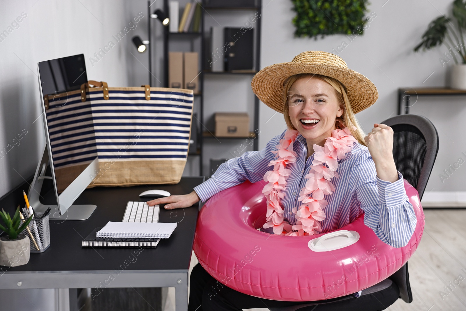 Photo of Businesswoman with inflatable ring, flower wreath, bag and straw hat at workplace in office