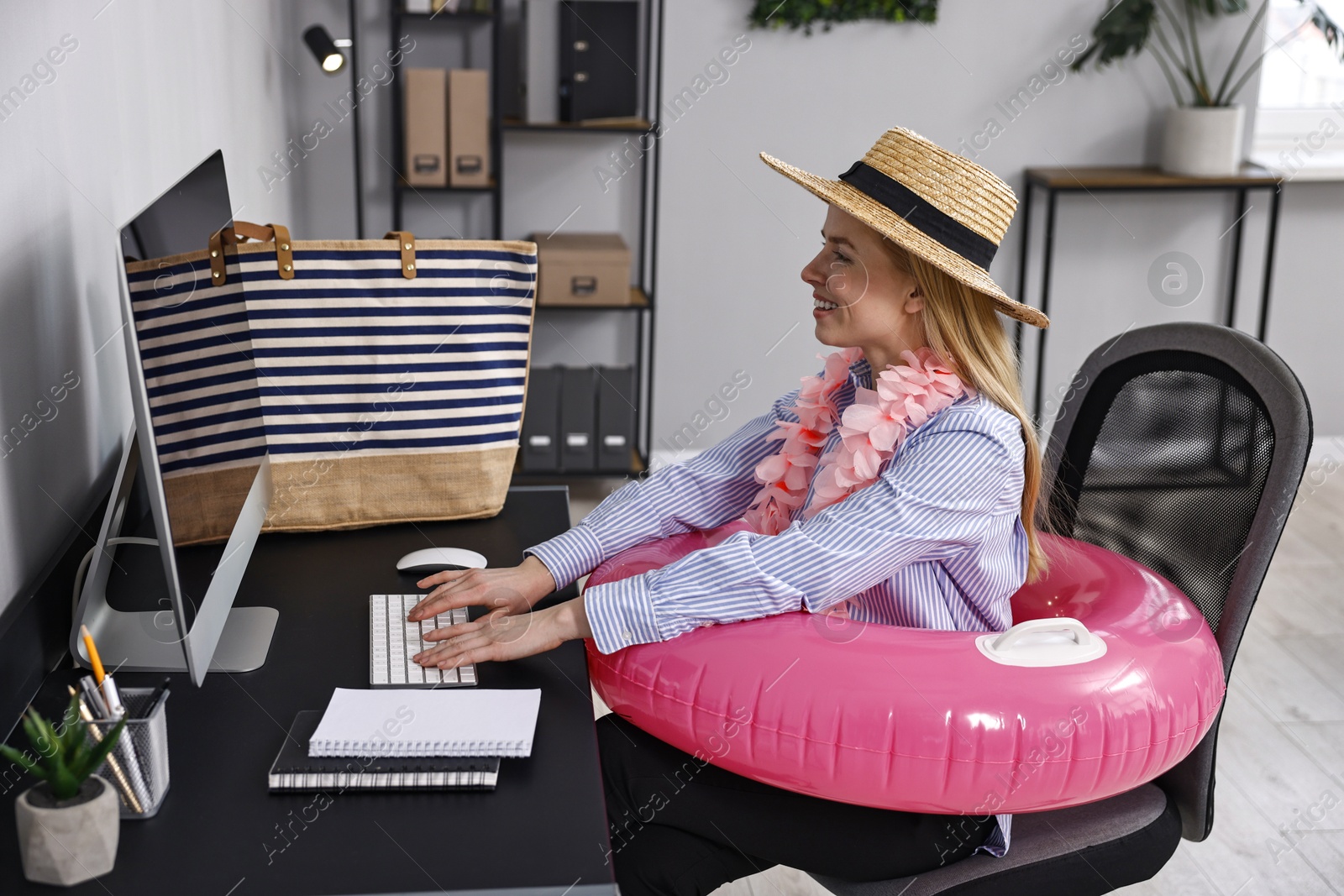 Photo of Businesswoman with inflatable ring, flower wreath, bag and straw hat at workplace in office