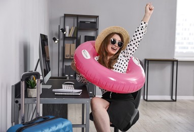 Photo of Businesswoman with inflatable ring, straw hat and sunglasses at workplace in office